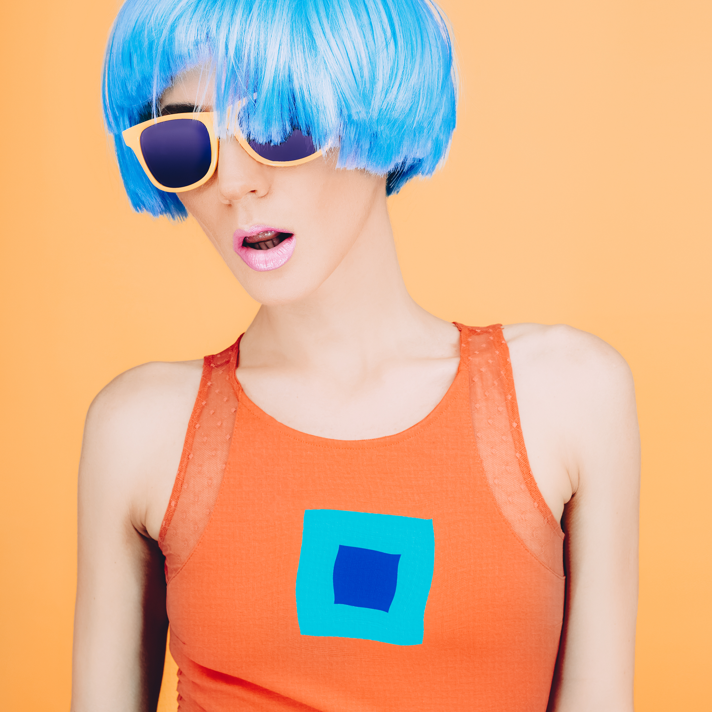 Fantastic party fashion lady in blue wig and glasses on yellow background